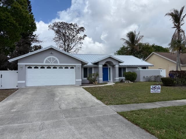 Gray South Florida home with a blue front door after exterior painting by Twils Painting